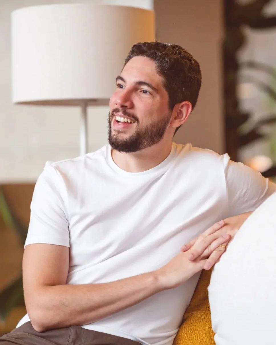 Fábio Alencar, founder of Vizlint, smiling on a sofa.